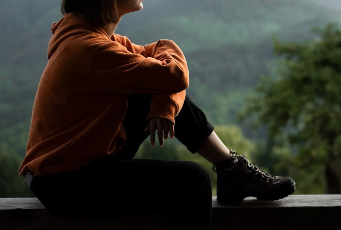 Susimąstęs žmogus ramioje aplinkoje, apmąstantis savo asmeninį tobulėjimą ir vidinę laisvę.