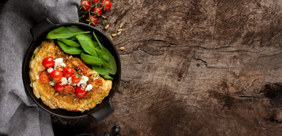 Ketaus keptuvė su paruoštu patiekalu ant medinio virtuvės stalo, pabrėžianti jos patvarumą ir tolygų šilumos paskirstymą.